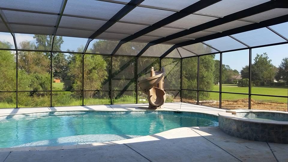 Screened pool and raised spa beneath dark aluminum framing